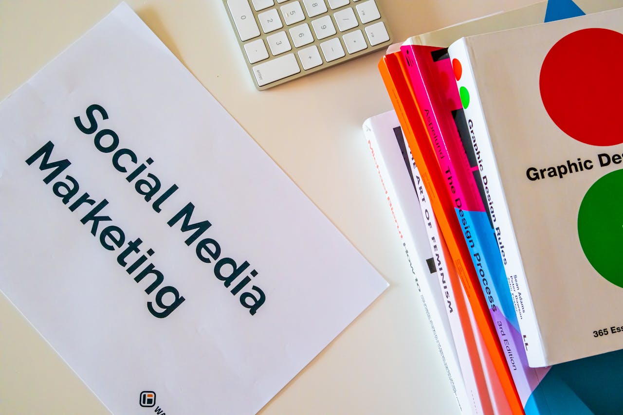 A top view of social media marketing text alongside graphic design books and a keyboard.